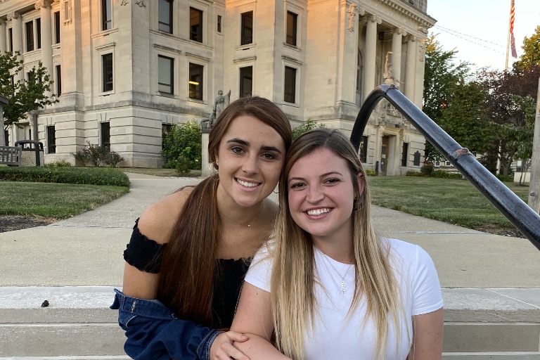 Emma Gerrety and a friend pose for photo on the steps outside the Bloomington courthouse